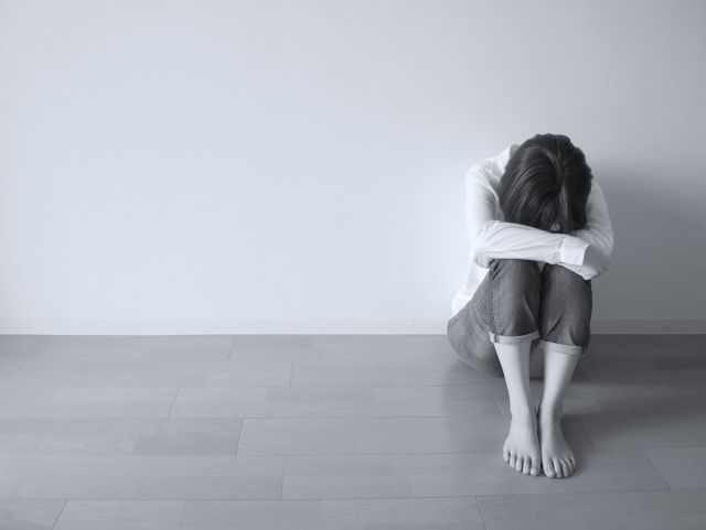 俯いて体育座りをしている人