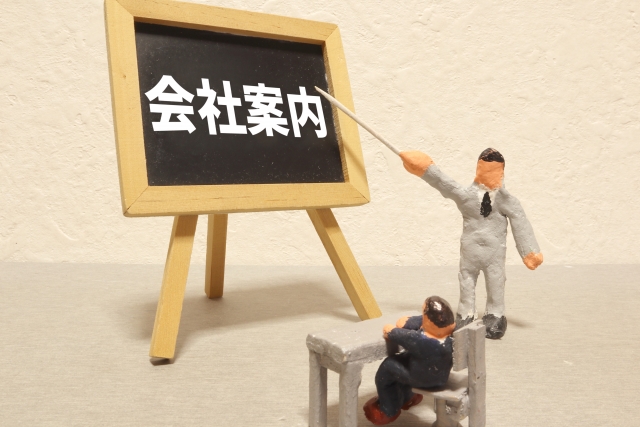 会社案内と書かれている黒板を指し示す人形