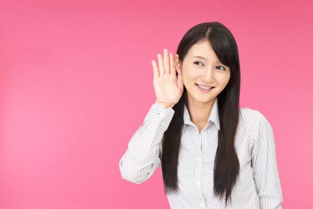 耳に手を当てて何かを聞こうとしている女性