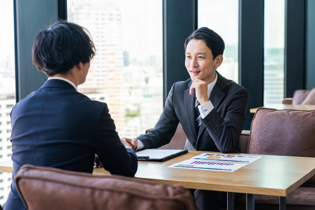 椅子に座って向き合う男性2人