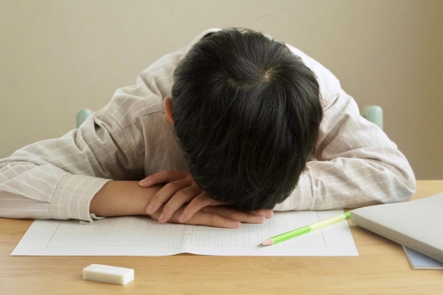机に顔を伏せている子供